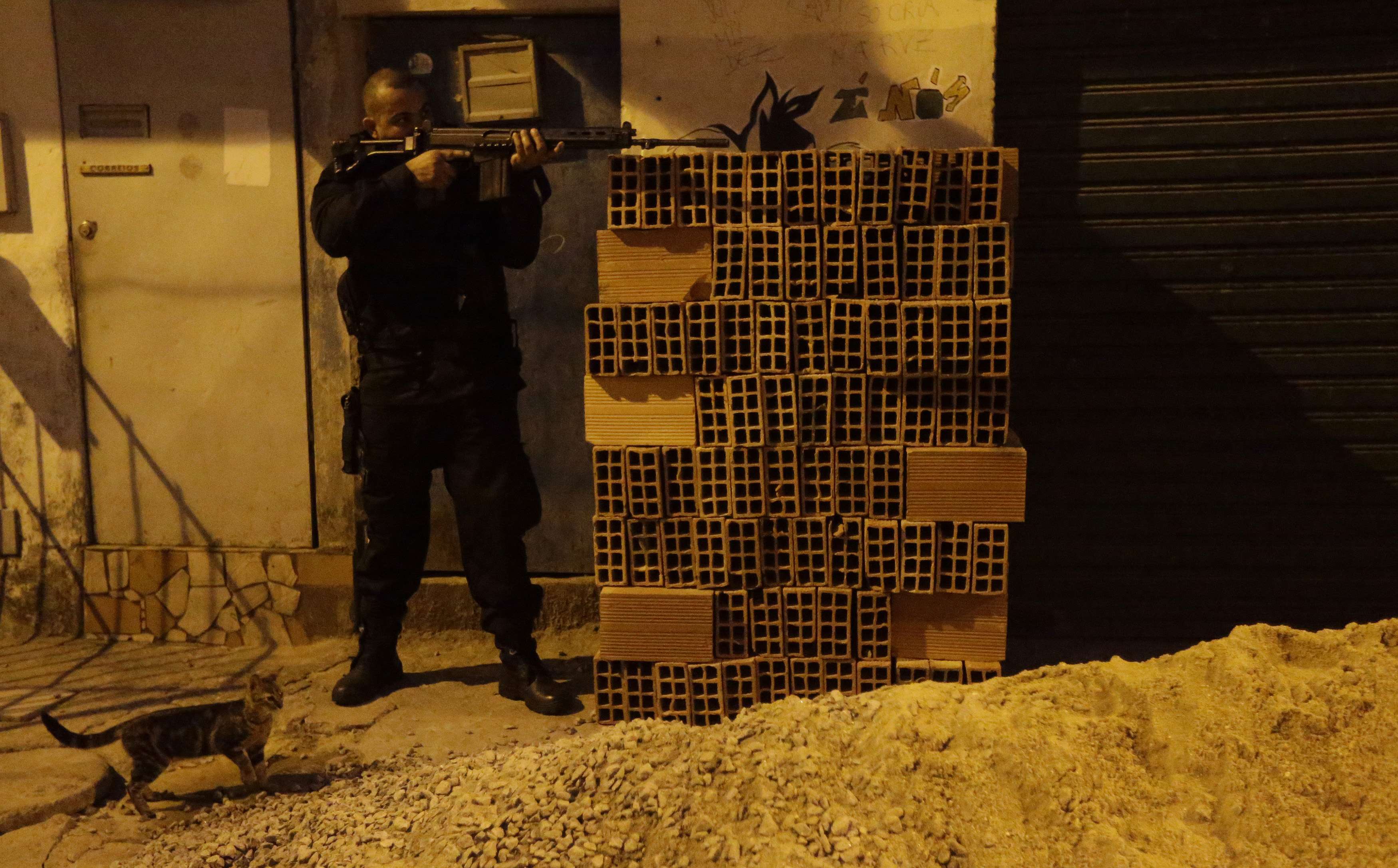 Agente das Forças de Segurança se posiciona com fuzil durante ocupação do Complexo da Maré | Ricardo Moraes/Reuters