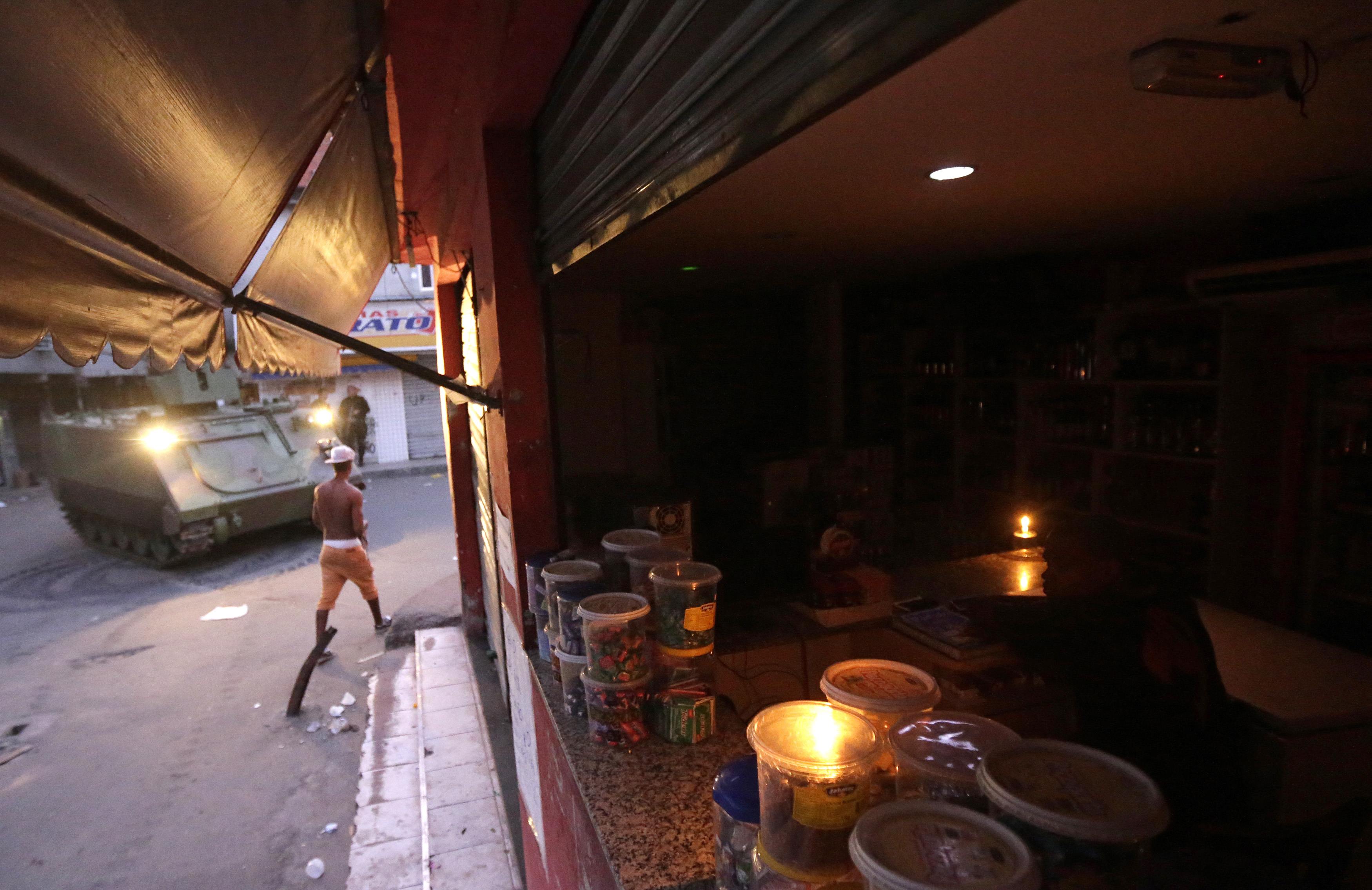 Homem trabalha enquanto blindados da Marinha brasileira ocupam o Complexo da Maré | Ricardo Moraes/Reuters