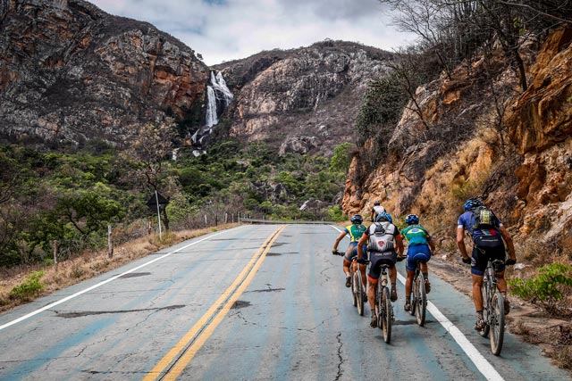 Ciclistas sobem a Serra Verde, em Rio de Contas, na 5ª etapa da ultramaratona Brasil Ride 2014, na Chapada Diamantina. No fundo, a visão espetacular de uma cachoeira | Fábio Piva/ Brasil Ride